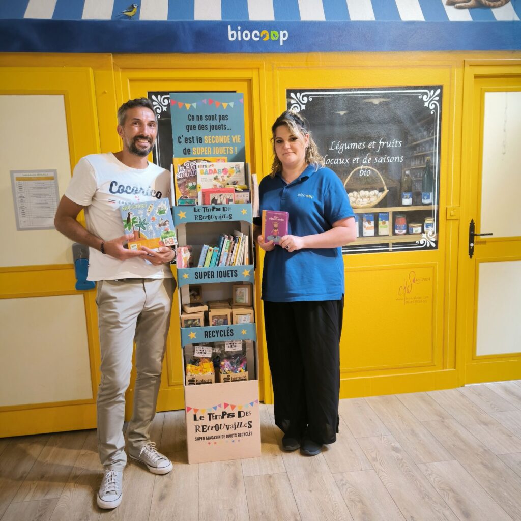 Photo d'un homme et une femme devant un présentoir de jouets d'occasion Le Temps des Retrouvailles